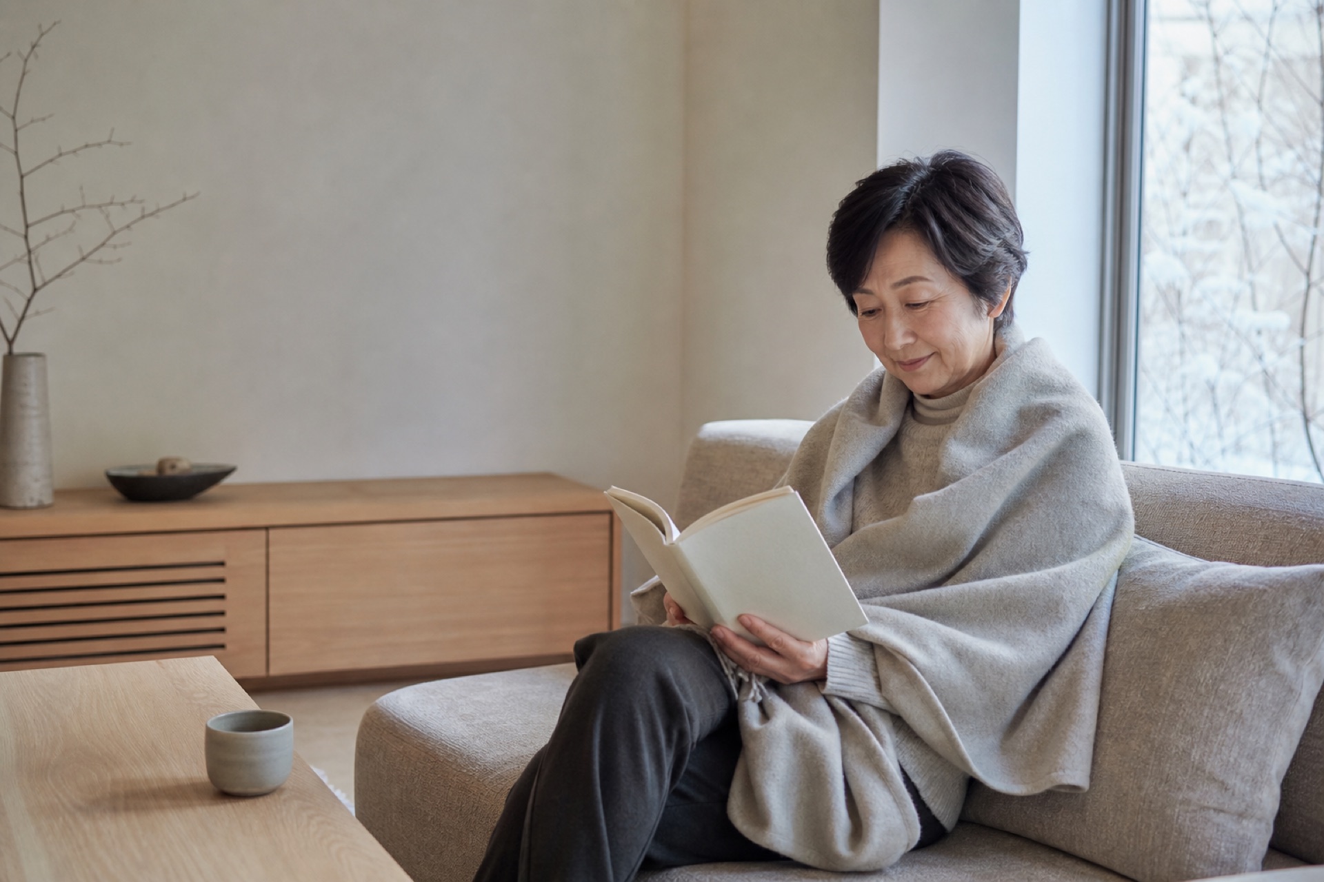 ブランケットを肩に掛けて読書をする女性